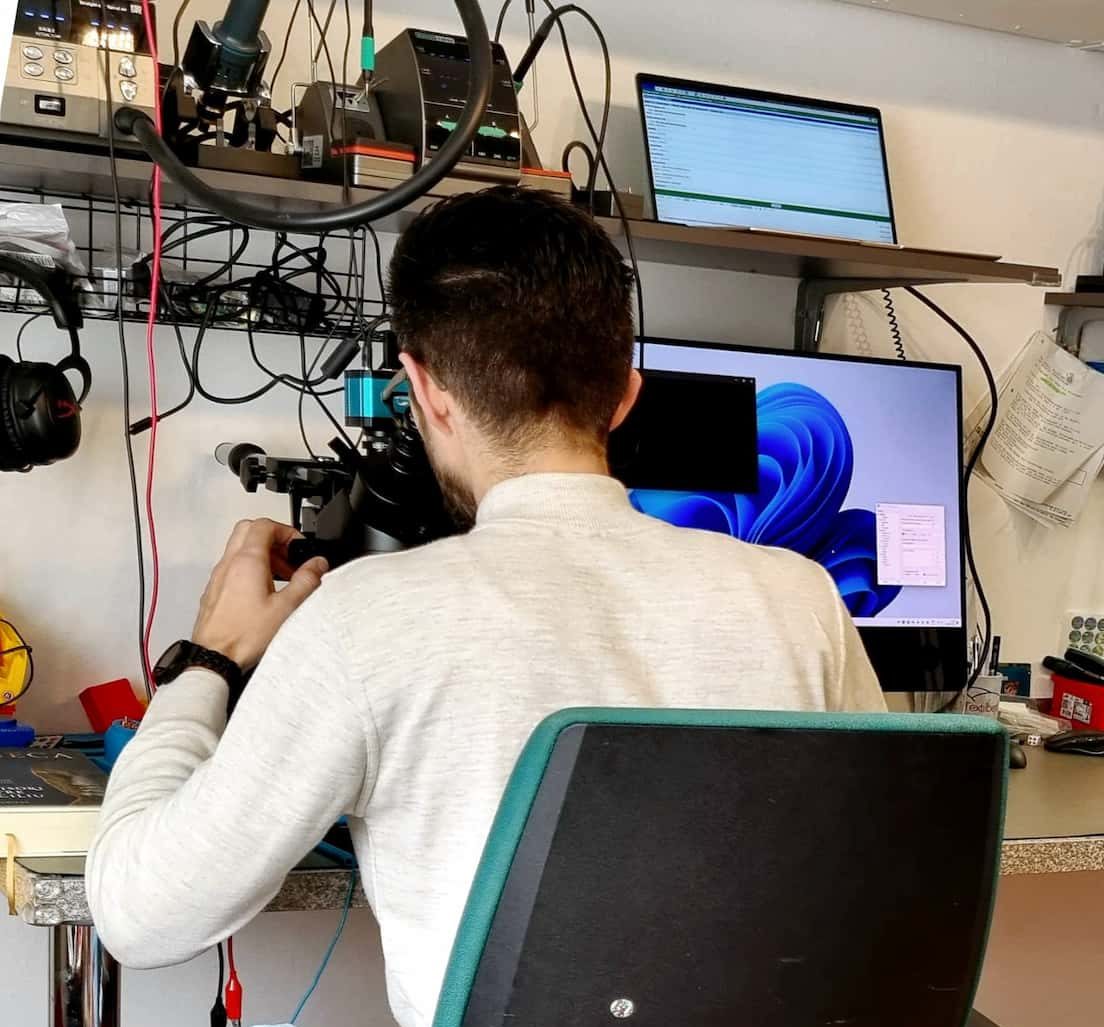 IT-Techniker arbeitet mit Mikroskop an Laptop-Reparatur in professioneller Werkstatt Kößlarn